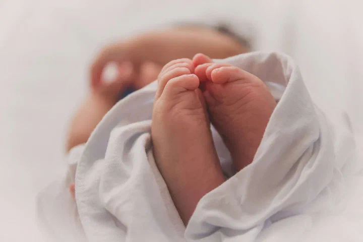 Picioarele unui bebeluș învelit într-o pătură albă