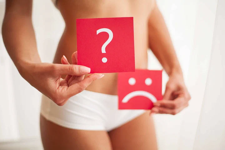 Femeie care ține două cartonașe ce simbolizează disconfortul abdominal