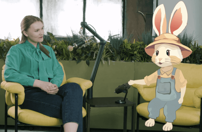 Imaginea arată un podcast în care o tânără discută cu iepurele animat Bioticel. Ei sunt așezați pe scaune galbene și au microfoane între ei.