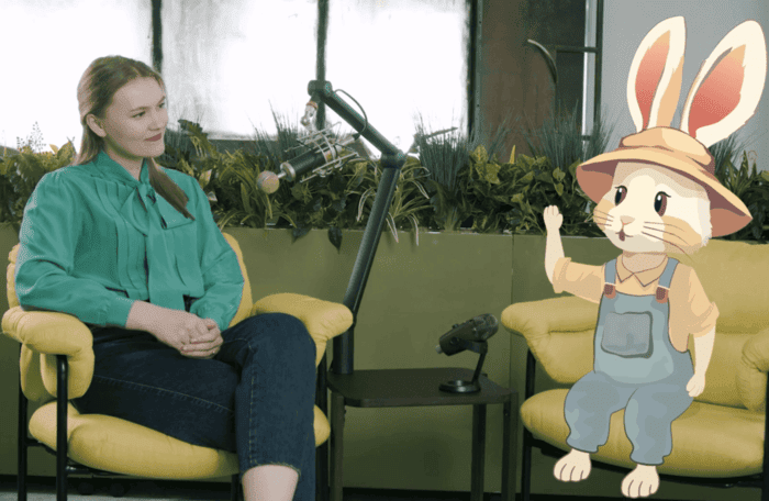Imaginea arată un podcast în care o tânără discută cu iepurele animat Bioticel. Ei sunt așezați pe scaune galbene și au microfoane între ei.
