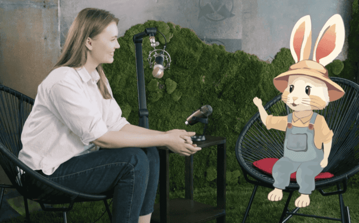 Imaginea arată un podcast în care o tânără discută cu iepurele animat Bioticel. Ei sunt așezați pe scaune, față în față și au un microfon între ei.